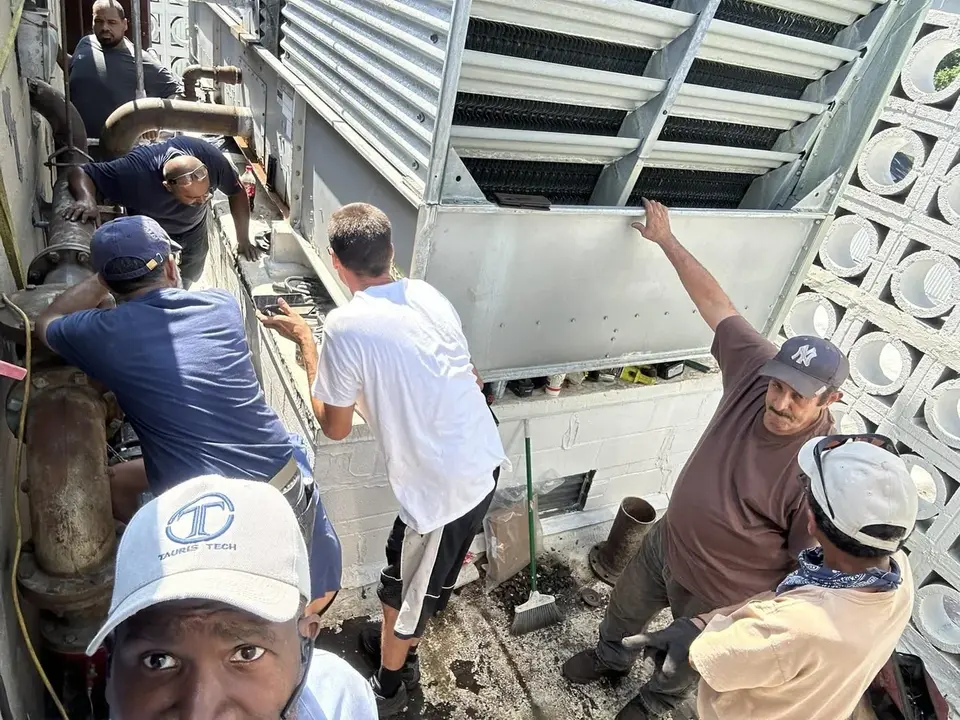 A crew lifting the access panel of a rooftop cooling tower in New York City