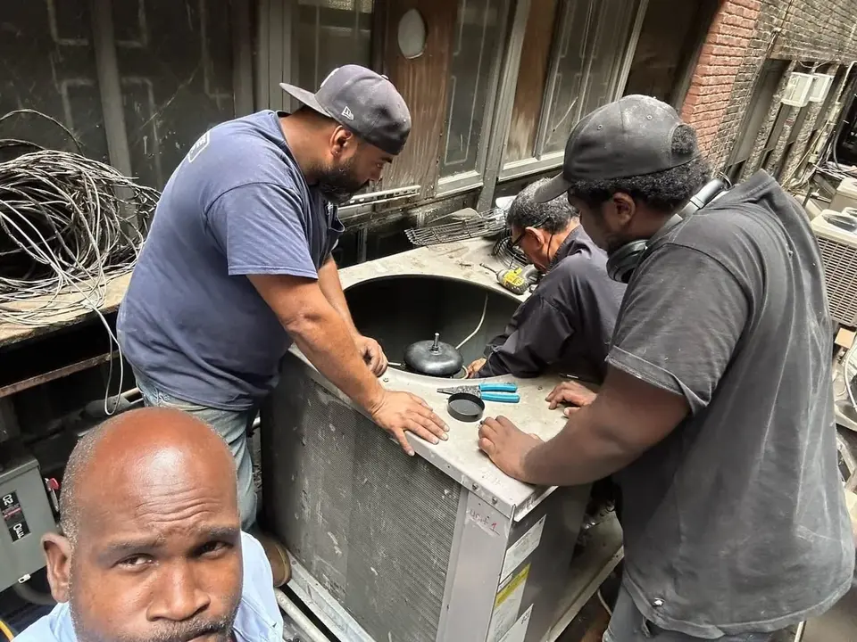 Three Tauris Tech technicians working inside an open rooftop condensing unit