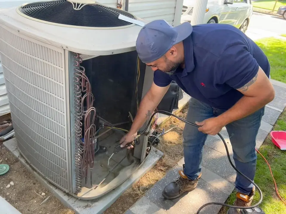 A Tauris Tech technician working inside an open residential condenser unit