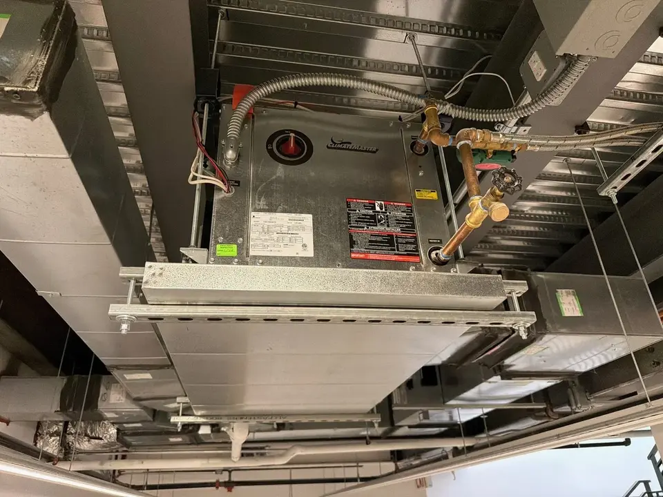 A ceiling-mounted unit in a New York City building, with its piping and controls